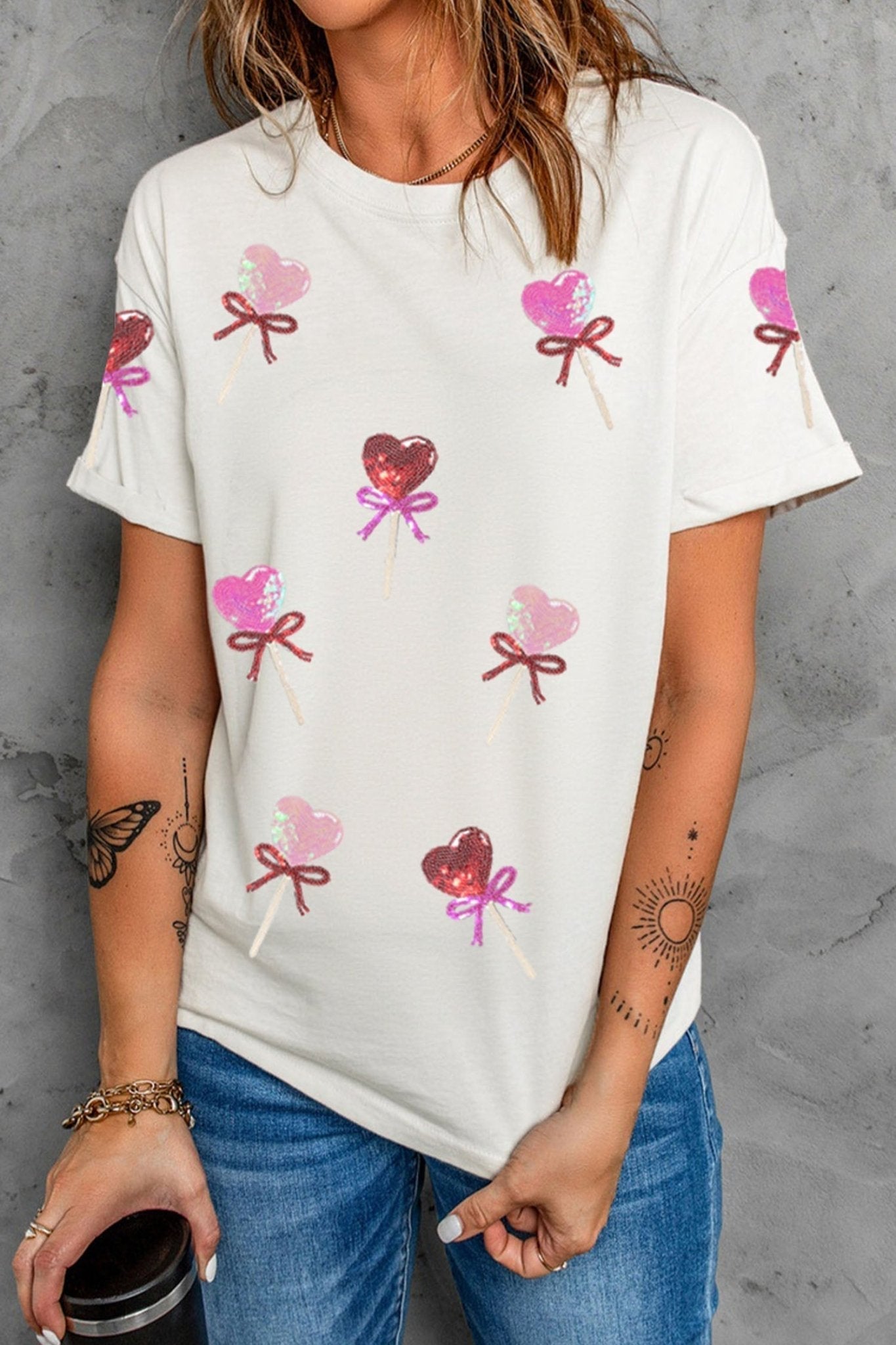 Person wearing a white t-shirt with heart and bow designs on a gray background