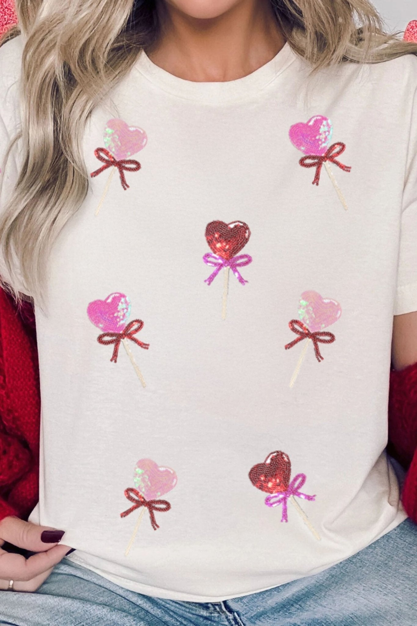 White t-shirt with heart and bow designs worn by a person.
