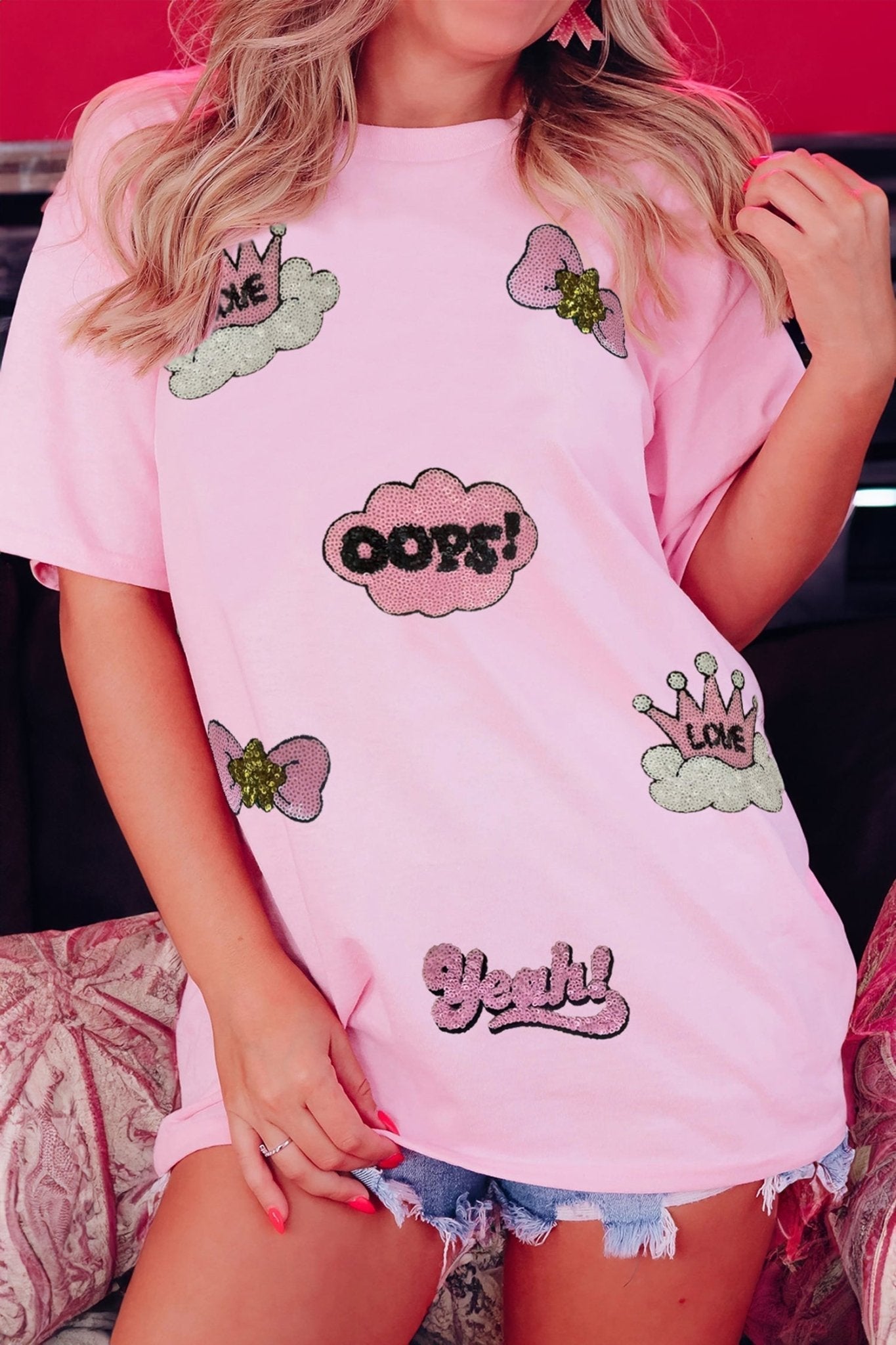 Person wearing a pink t-shirt with various designs and text.