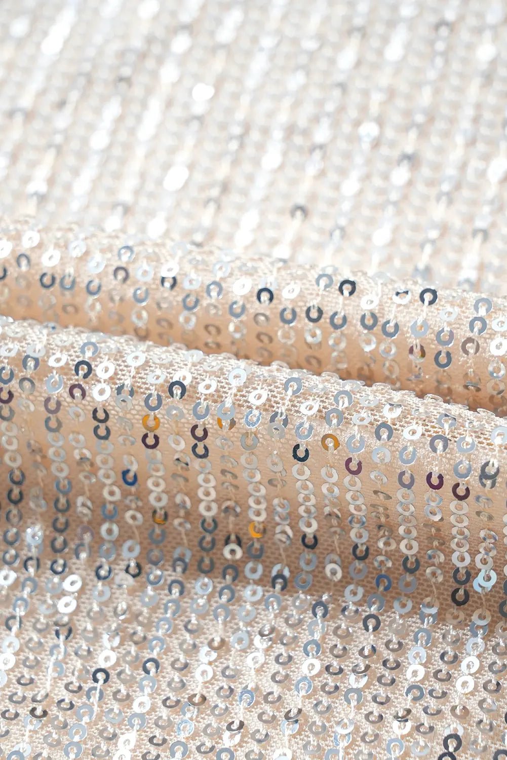 Close-up of a fabric with silver sequins on a beige background