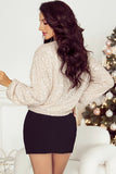 Woman wearing a sparkly beige top and black skirt in a festive setting with a Christmas tree.
