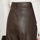 Brown leather pants worn by a person on a light background