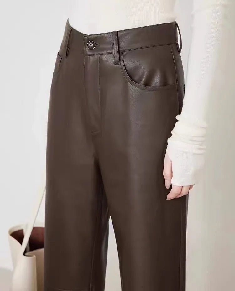 Brown leather pants worn by a person on a plain background