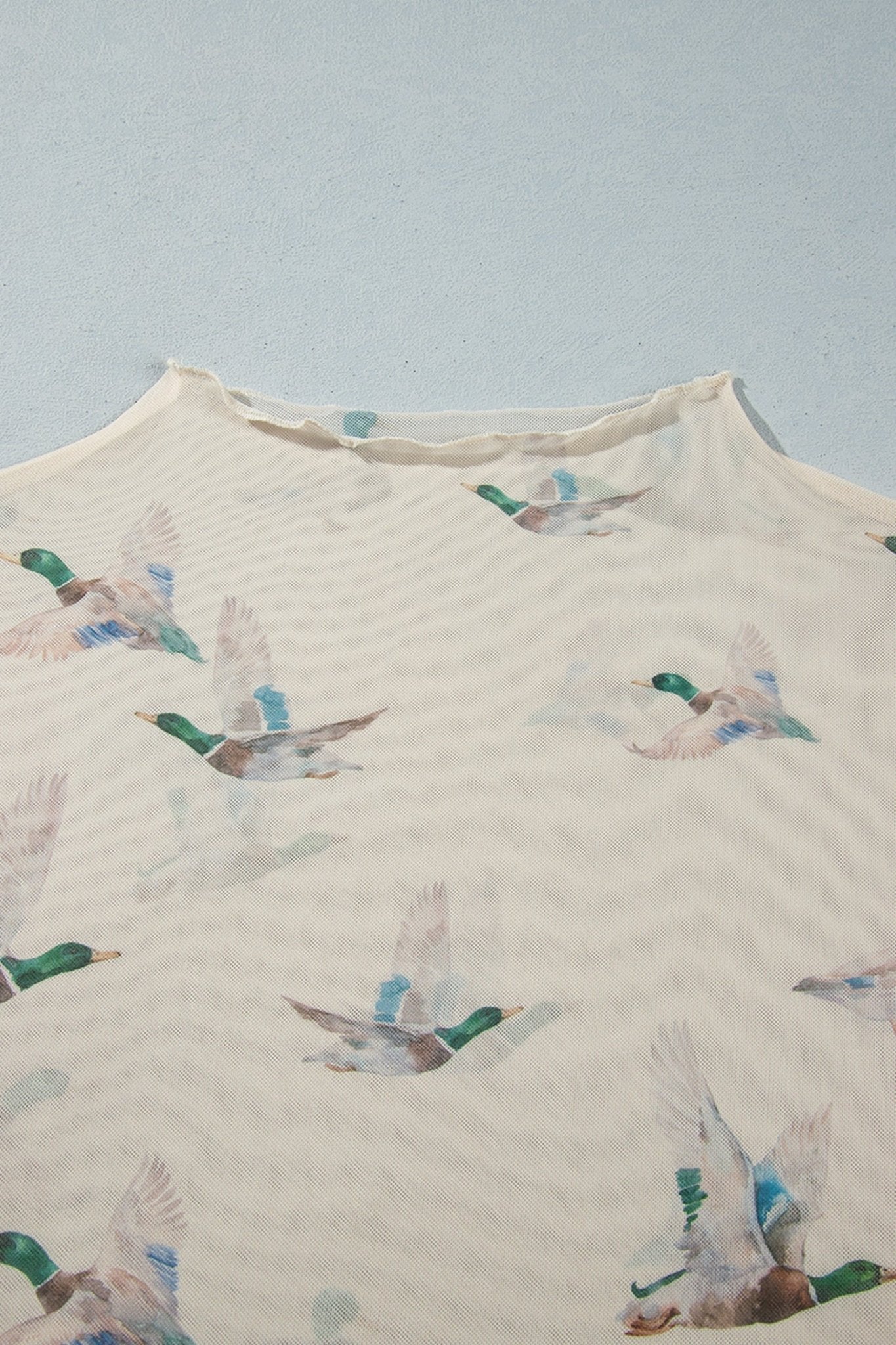 Cream garment with repeating flying mallard print in green, blue, and brown.