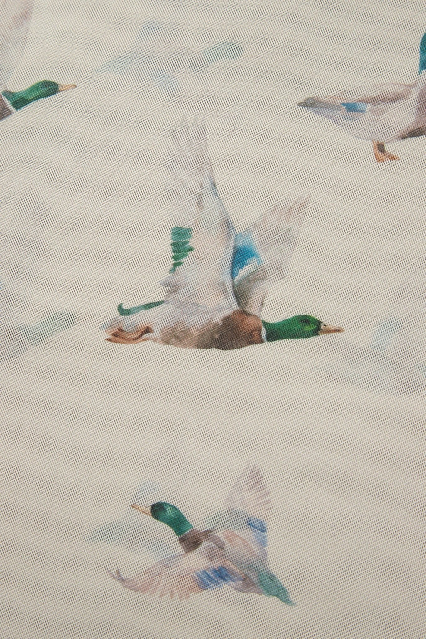 A close-up of a fabric or wallpaper pattern featuring mallards in flight on a light beige textured background.