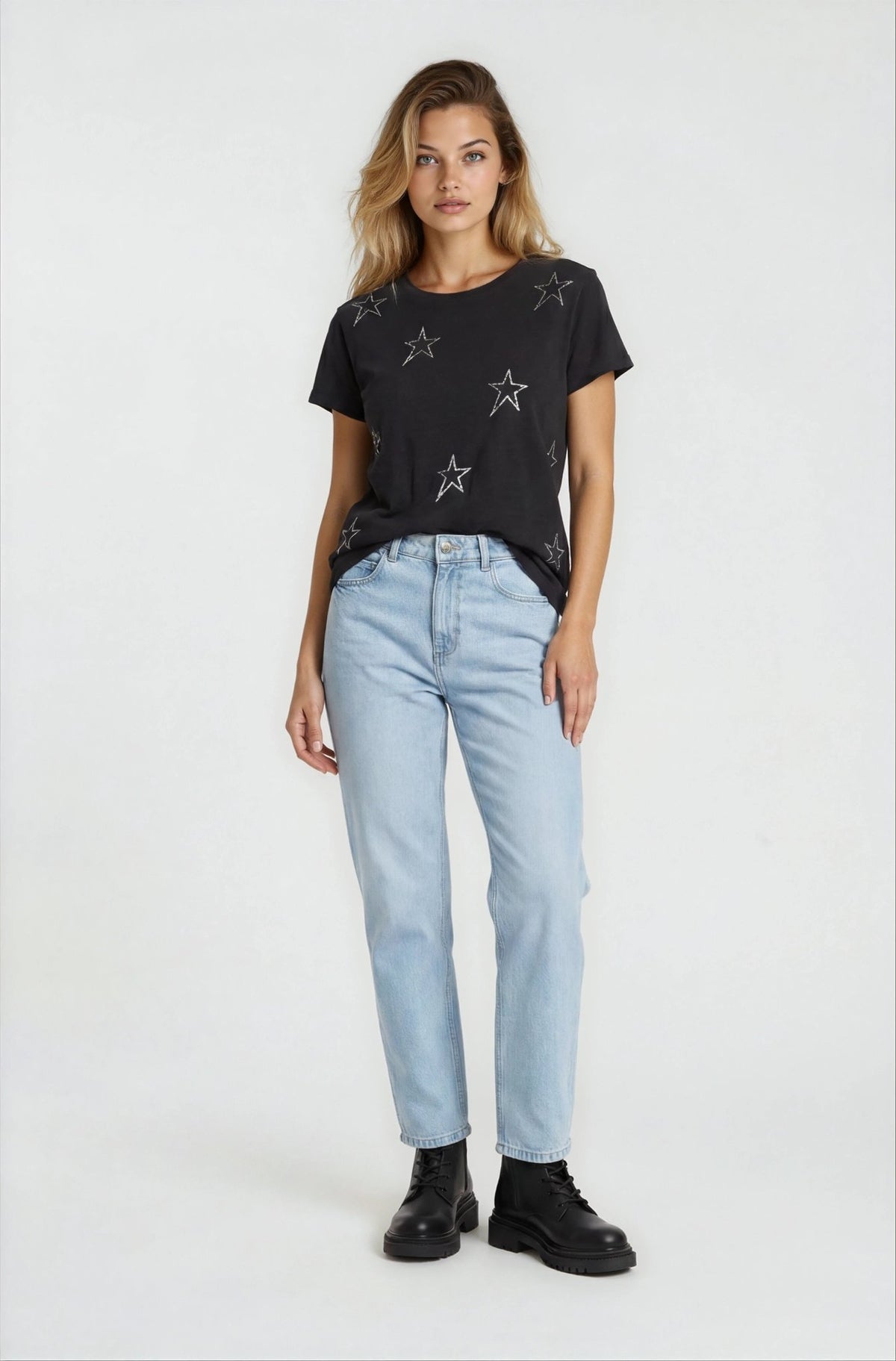 Woman wearing a black t-shirt with star patterns and light blue jeans on a white background