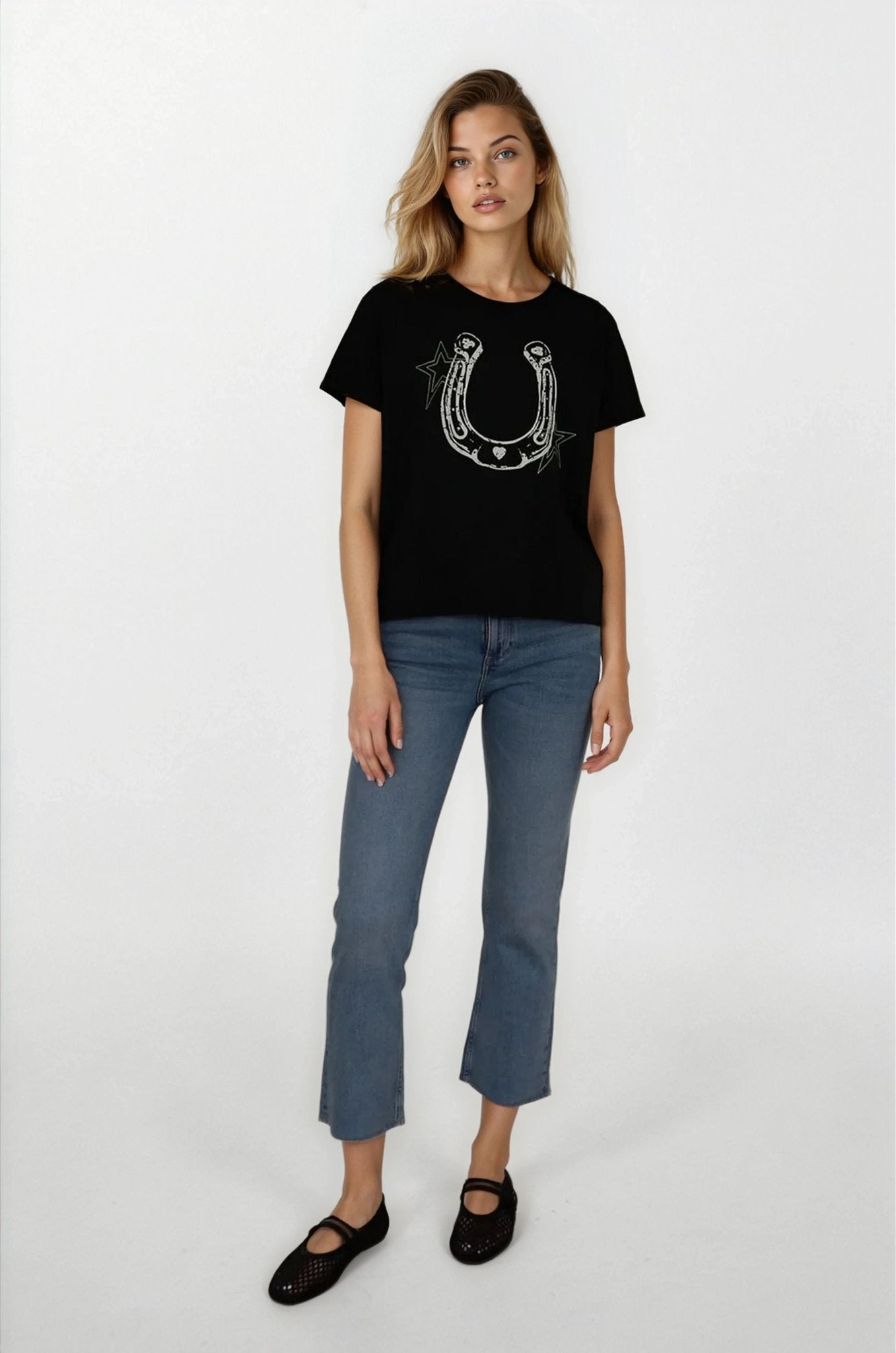 Woman wearing a black t-shirt with a horseshoe design and blue jeans on a white background