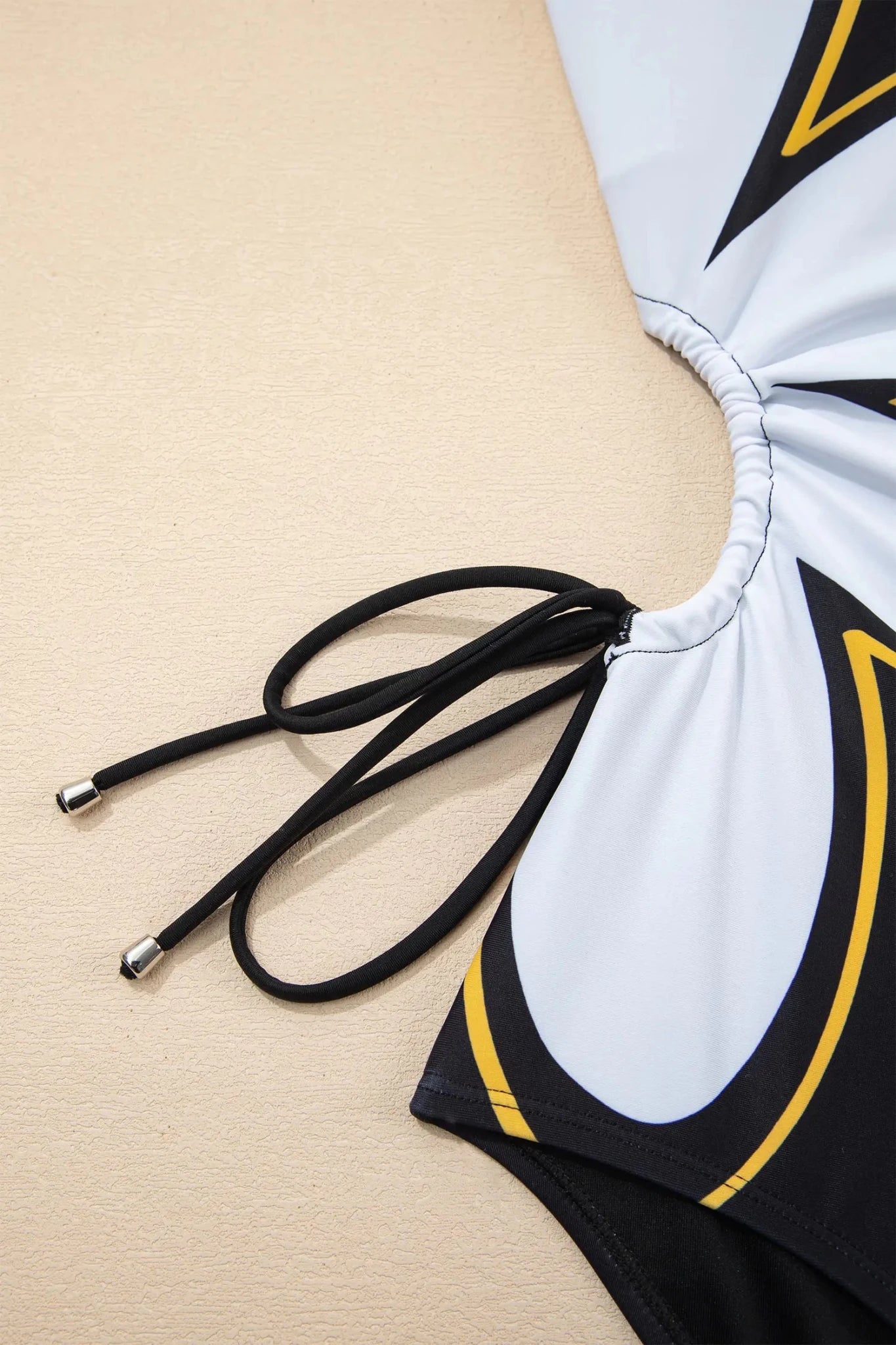 Black and white swimsuit with yellow accents on a beige background