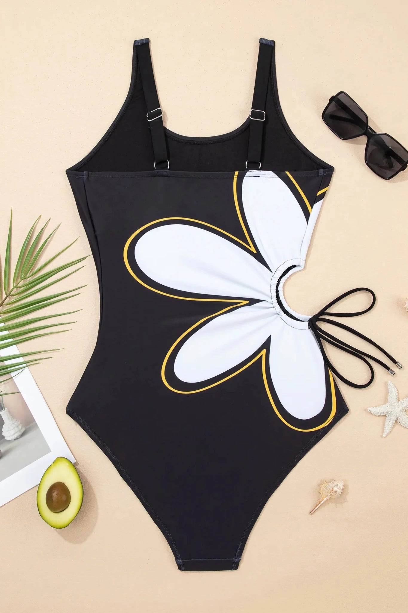 Black swimsuit with butterfly design on a beige surface