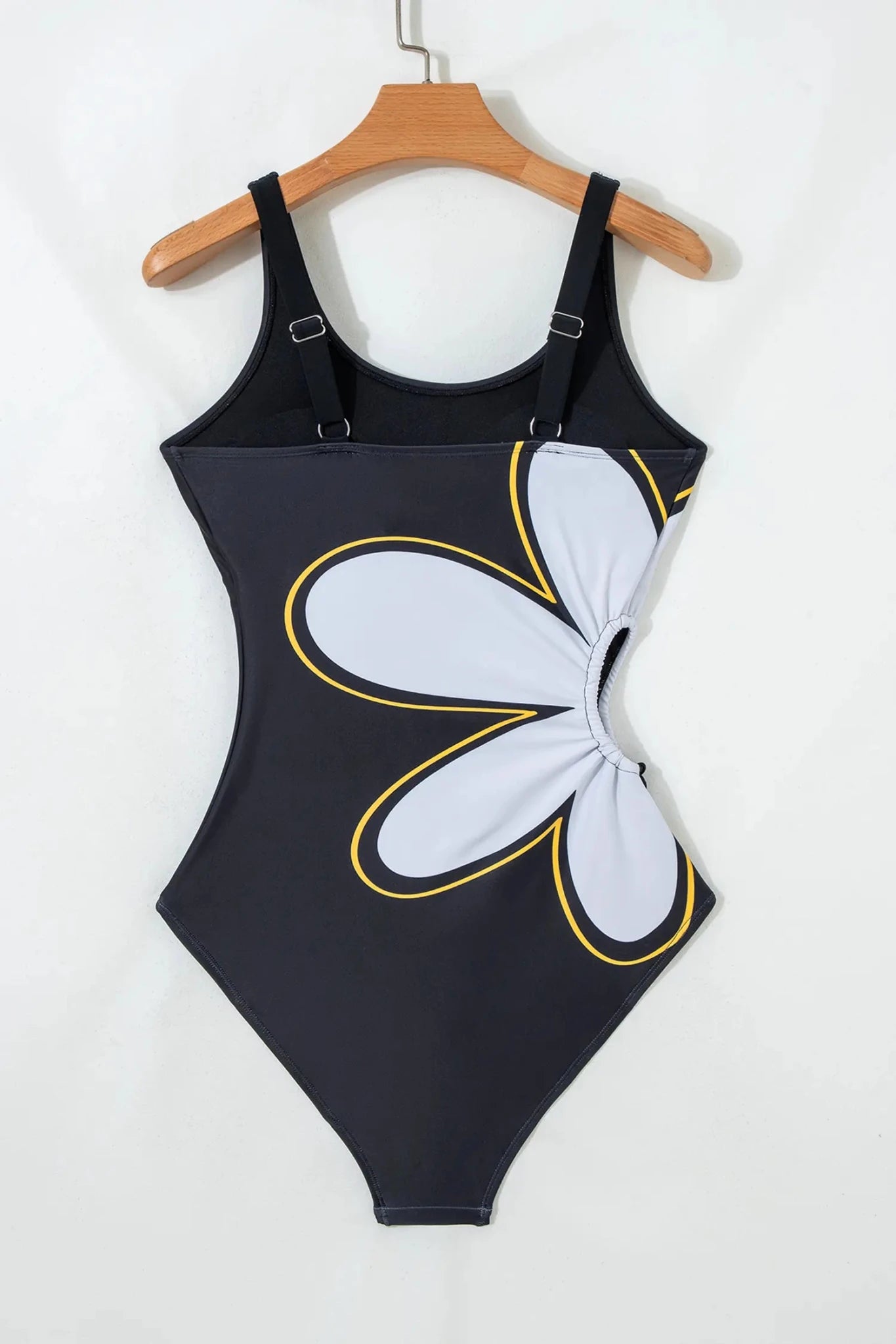 Black swimsuit with a white floral design on a hanger against a white background