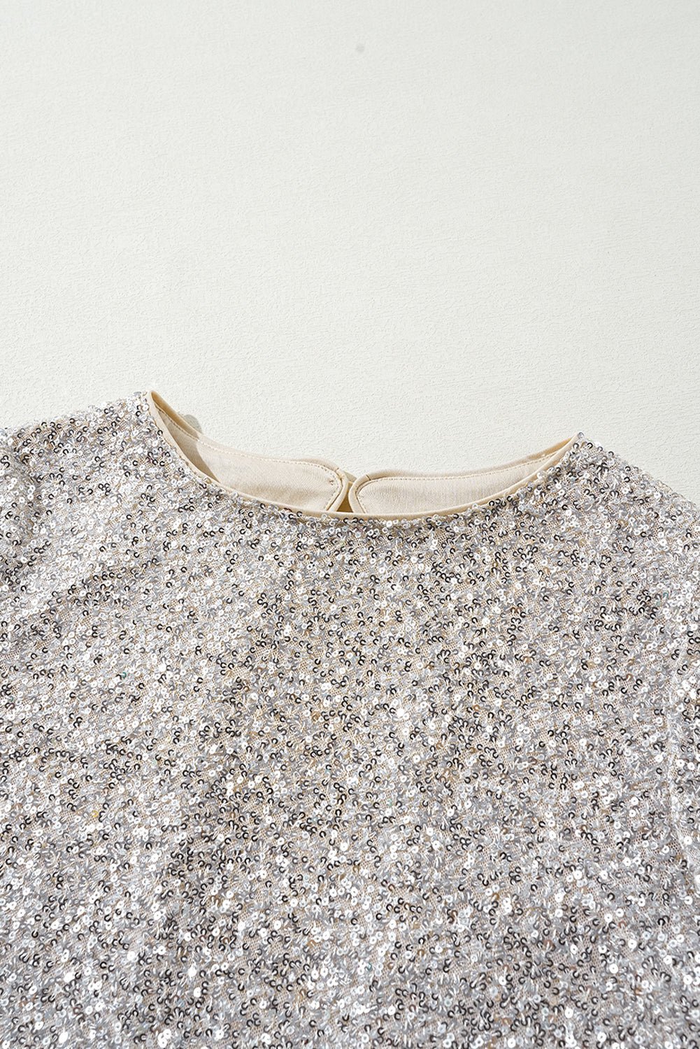 Close-up of a silver glittery fabric with a gold trim on a white background