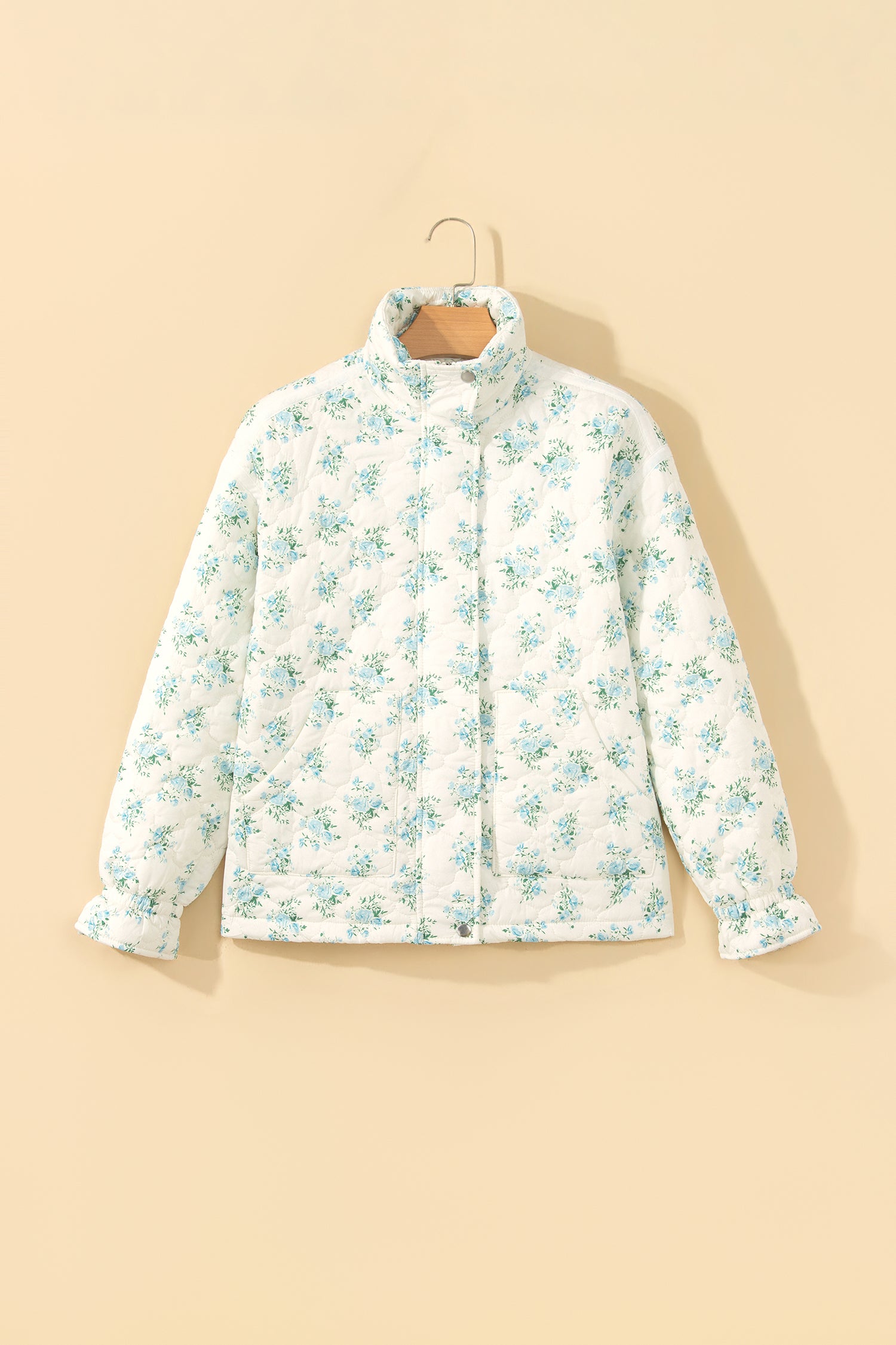 Sky blue floral quilted puffer jacket with stand collar and ruffle cuffs on a hanger