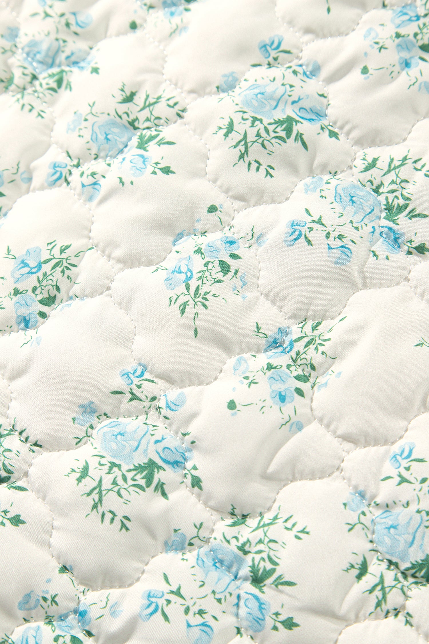 Close-up of scalloped cloud quilting on sky blue floral puffer fabric