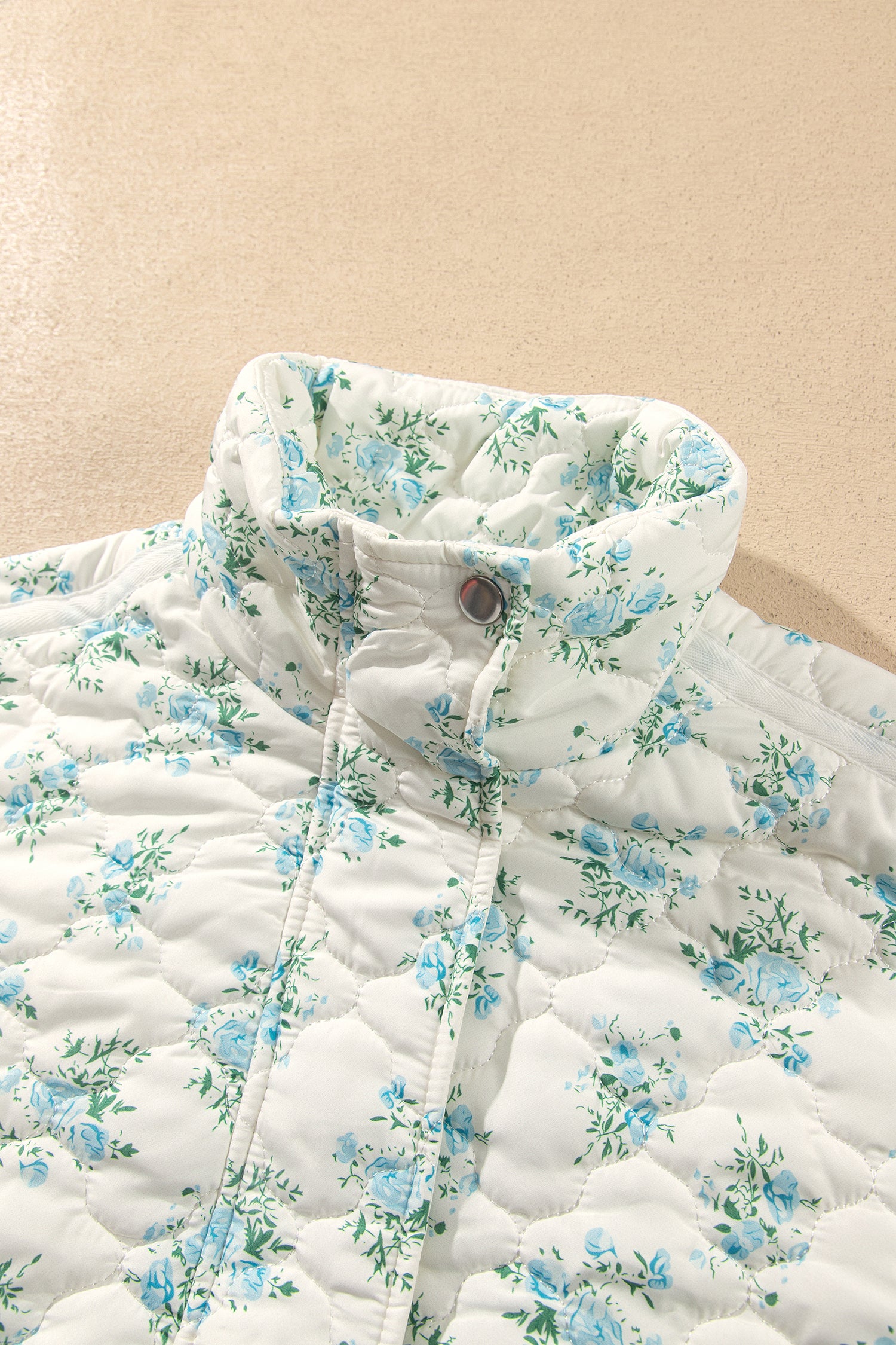 Close-up of stand collar and snap placket on sky blue floral quilted puffer jacket
