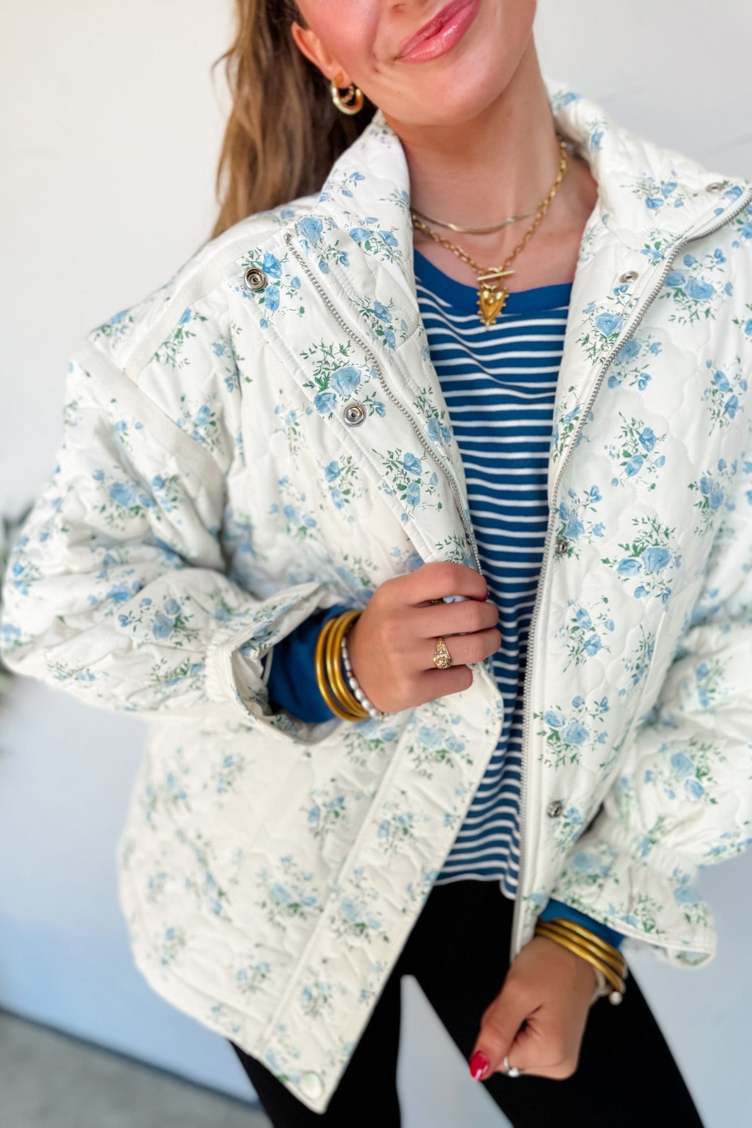 Woman in sky blue floral quilted puffer jacket with striped tee and black pants
