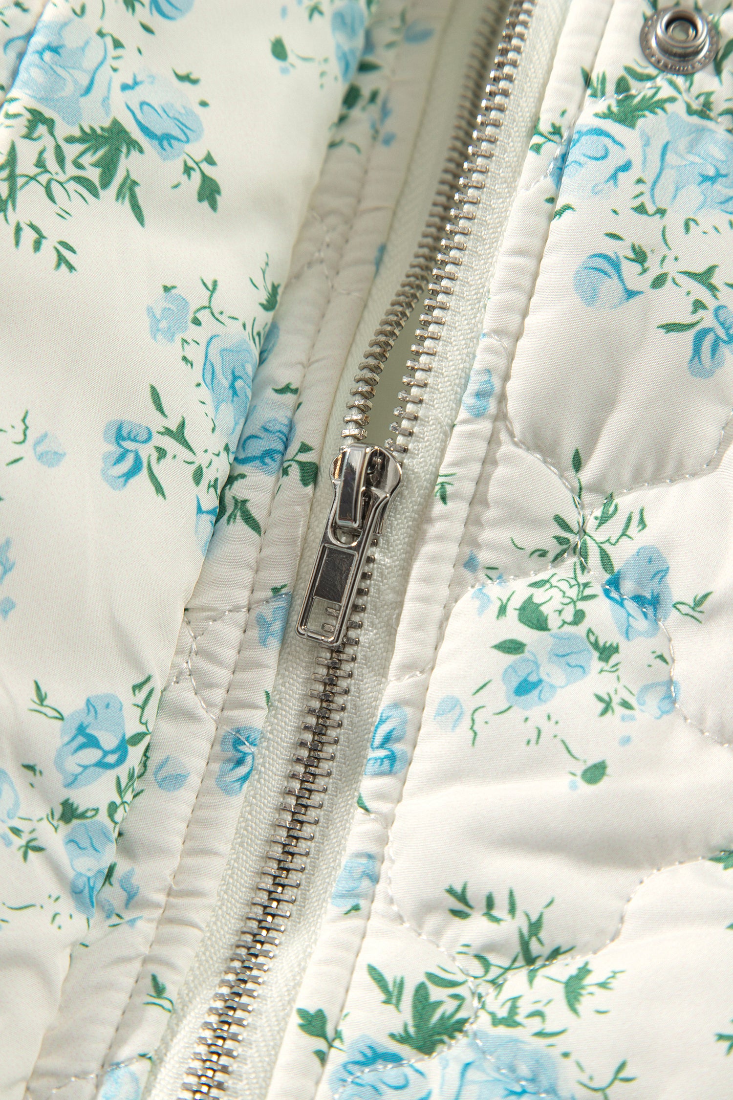 Close-up of metal zipper on sky blue floral quilted puffer jacket