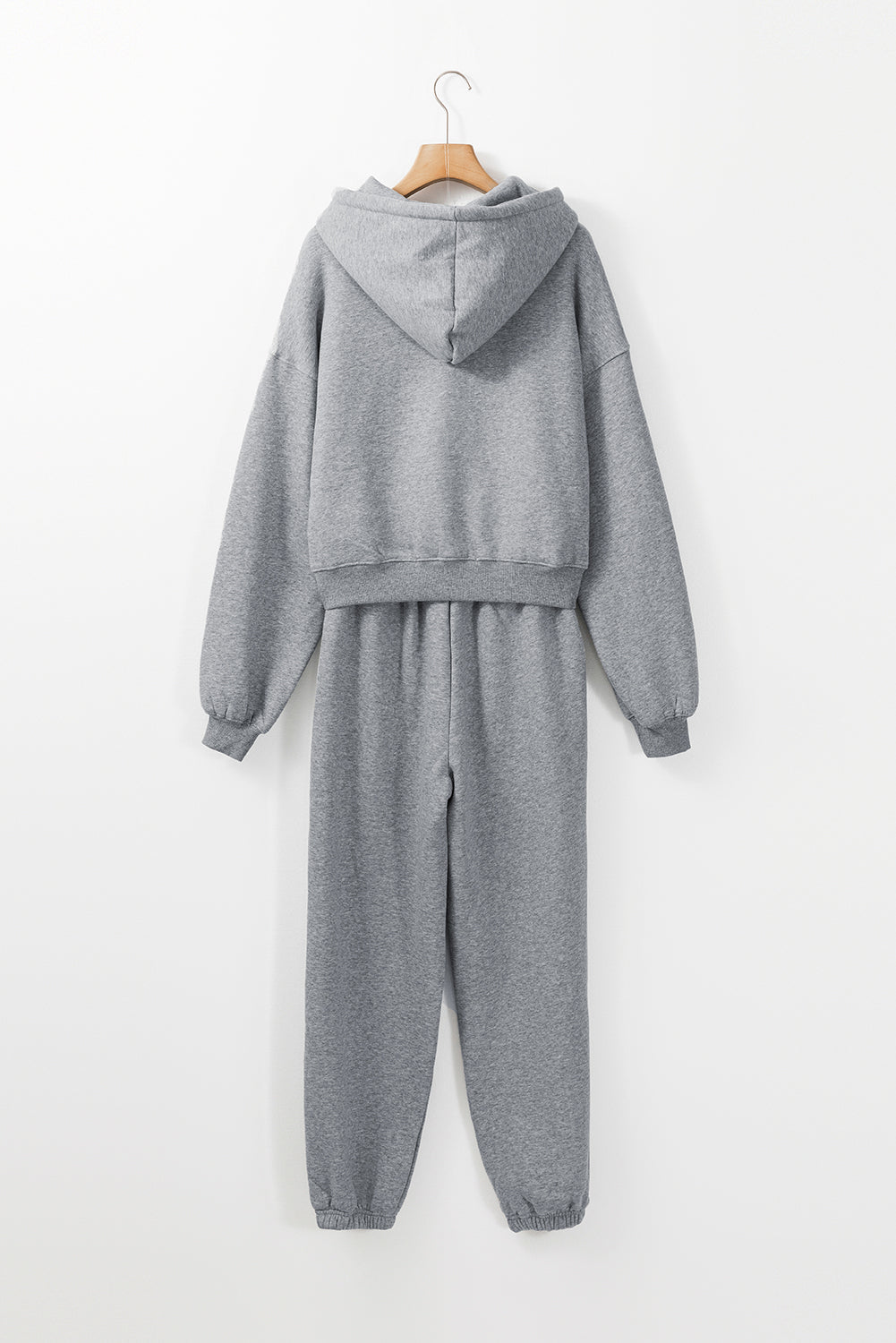 Gray tracksuit on a hanger against a white background