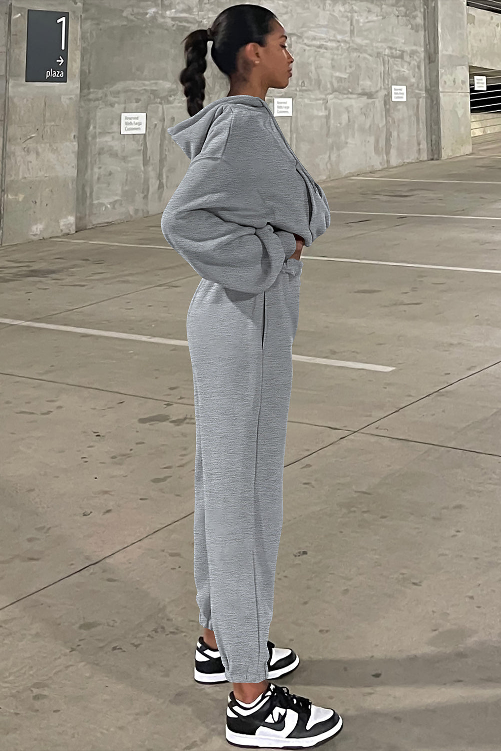 Person wearing a gray tracksuit standing in an outdoor setting.