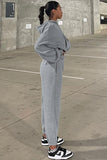 Person wearing a gray tracksuit standing in an outdoor setting.