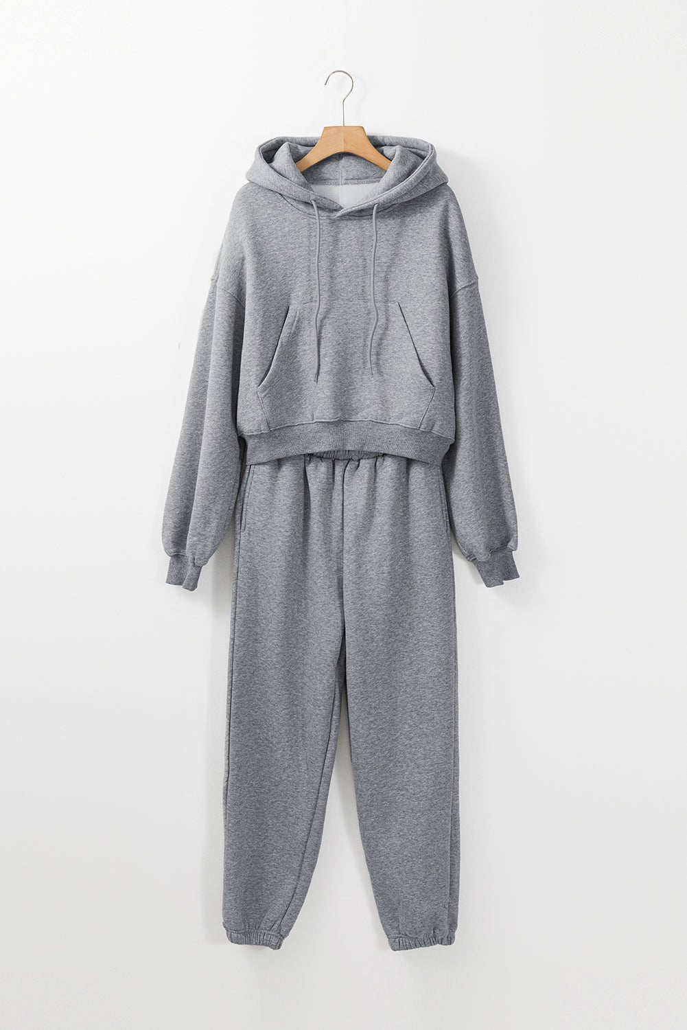 Gray hoodie and jogger set on a hanger against a white background