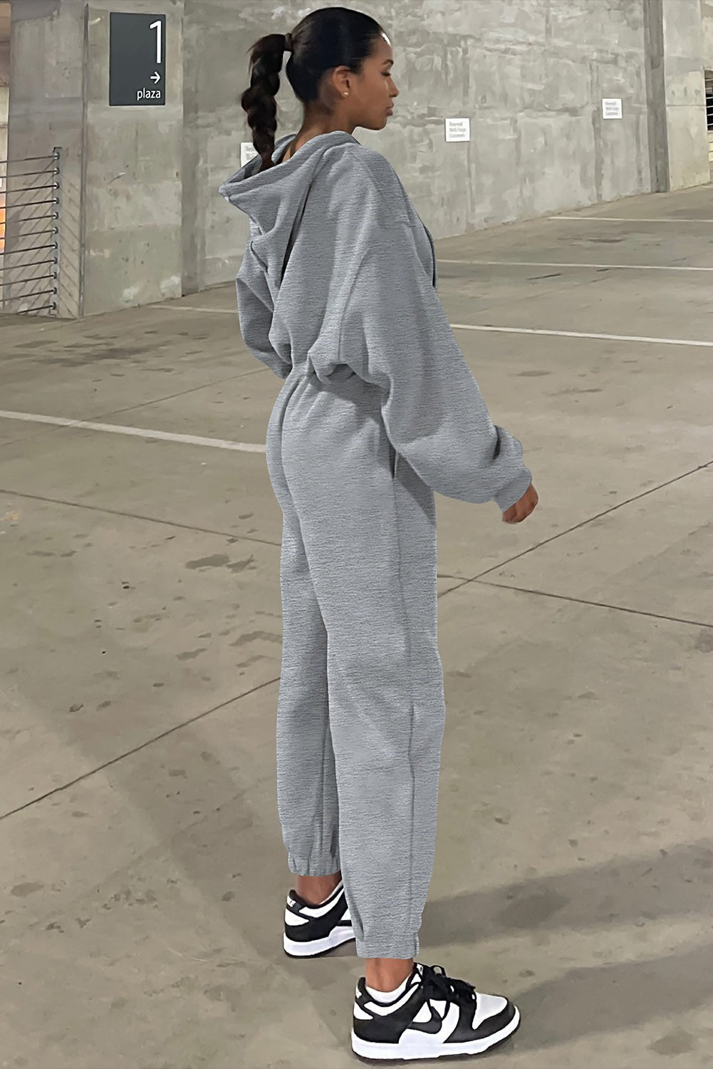 Person wearing a gray tracksuit standing on a concrete pavement.