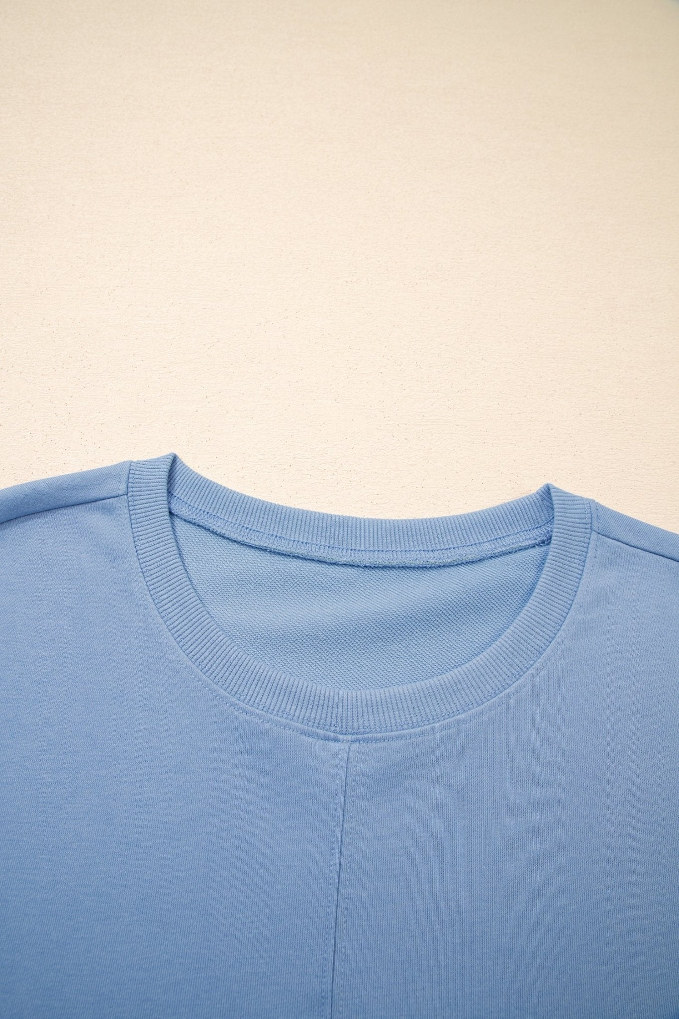 Close-up of a light blue shirt collar on a beige background