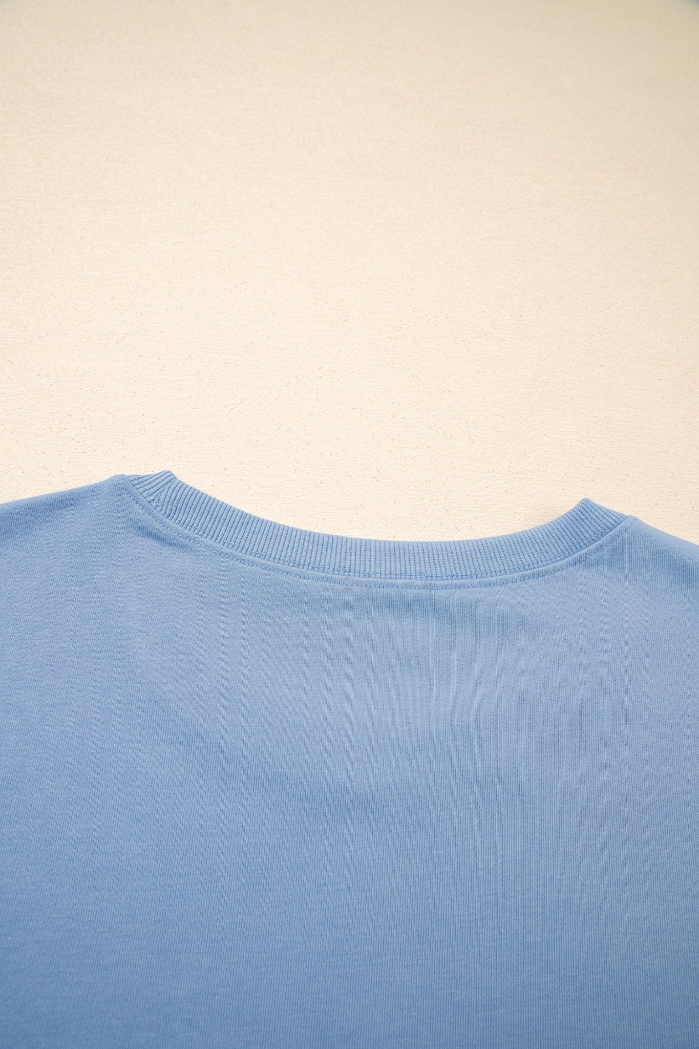 Close-up of a light blue sweater collar on a beige background