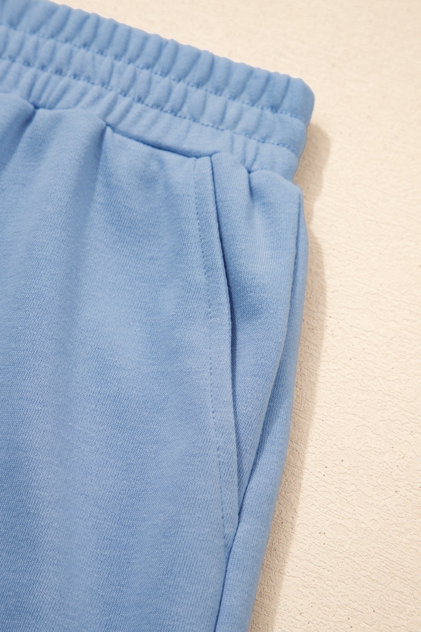 Close-up of blue sweatpants on a beige background