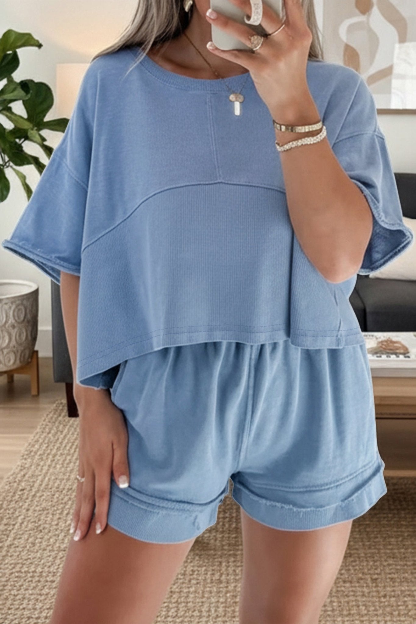 Woman wearing a blue outfit with a top and shorts in a living room setting.
