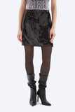 Person wearing a black sequin skirt, black tights, and black high-heeled boots on a white background.