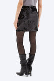 Person wearing a black sequin skirt and black high-heeled boots on a white background