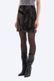 Person wearing a black sequin skirt and black knee-high boots on a white background