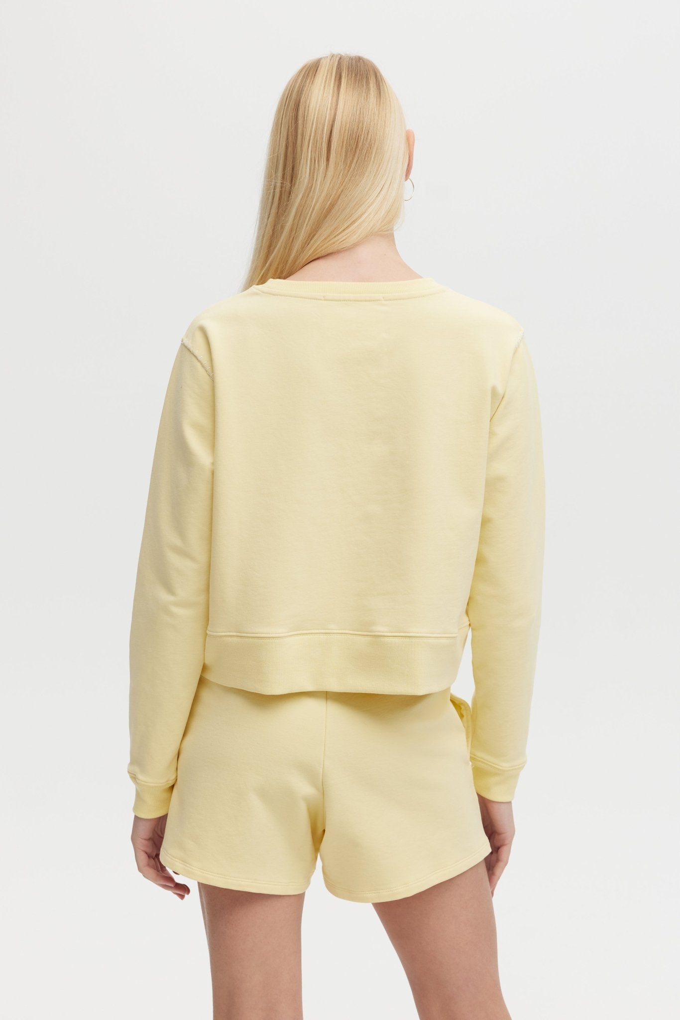 Woman wearing a yellow outfit with a plain background