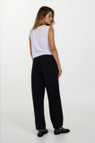 Woman wearing a white sleeveless top and black pants on a white background