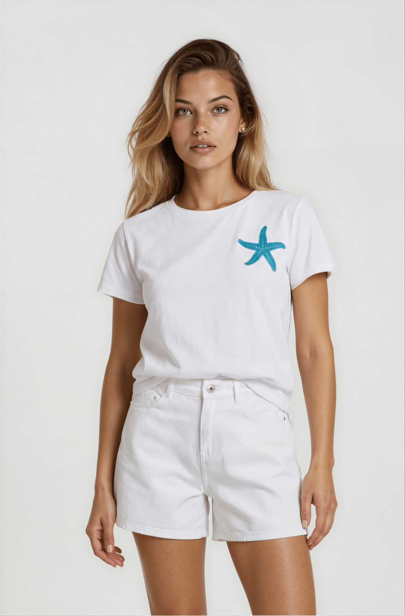 Woman wearing a white t-shirt with a blue starfish design and white shorts on a plain background