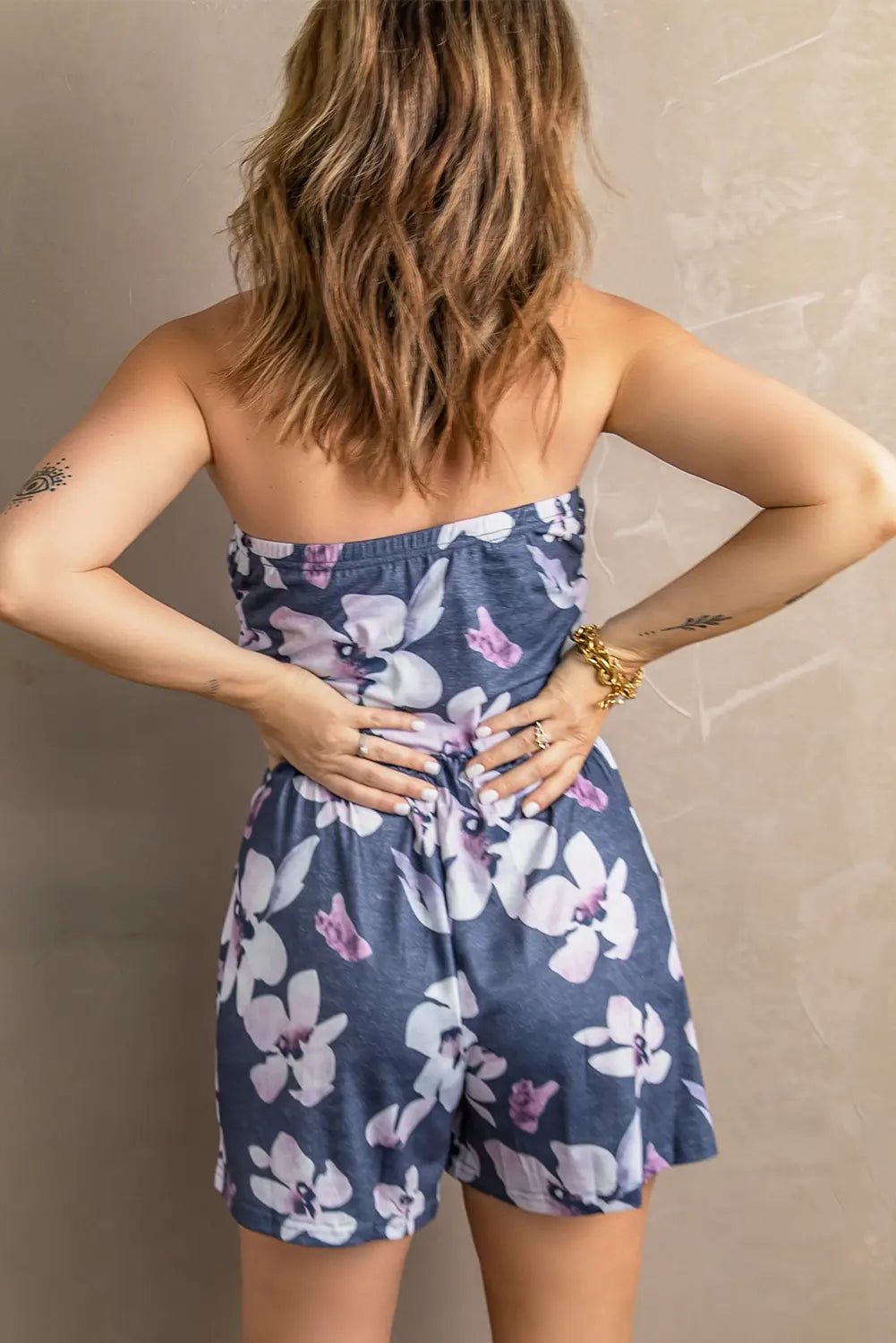 Woman wearing a strapless floral romper against a neutral background