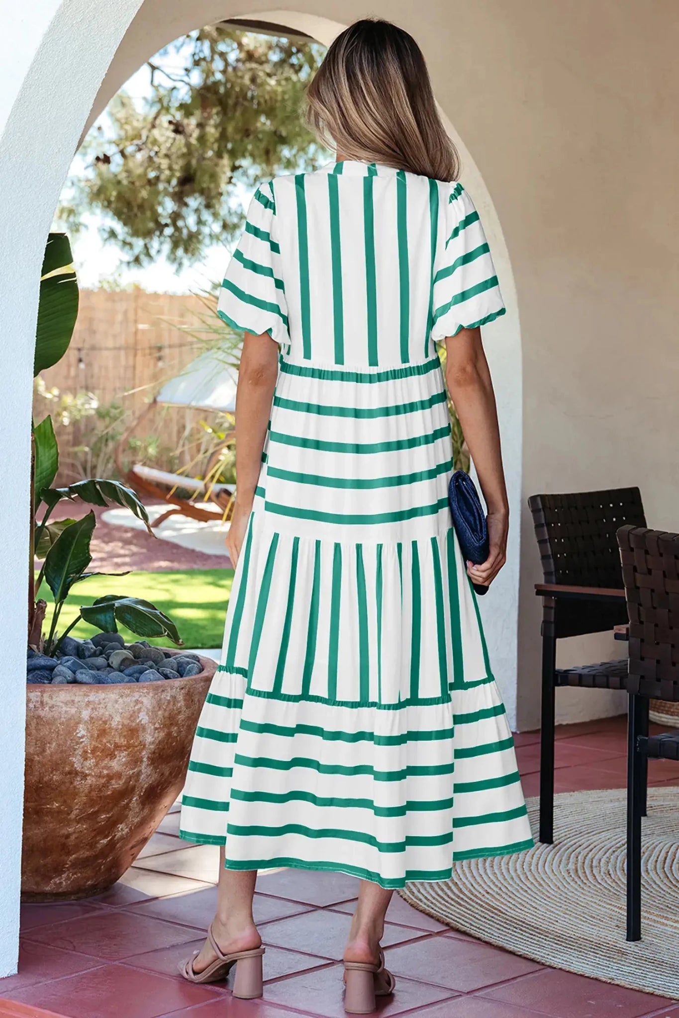 Woman wearing a green and white striped dress in an outdoor setting.