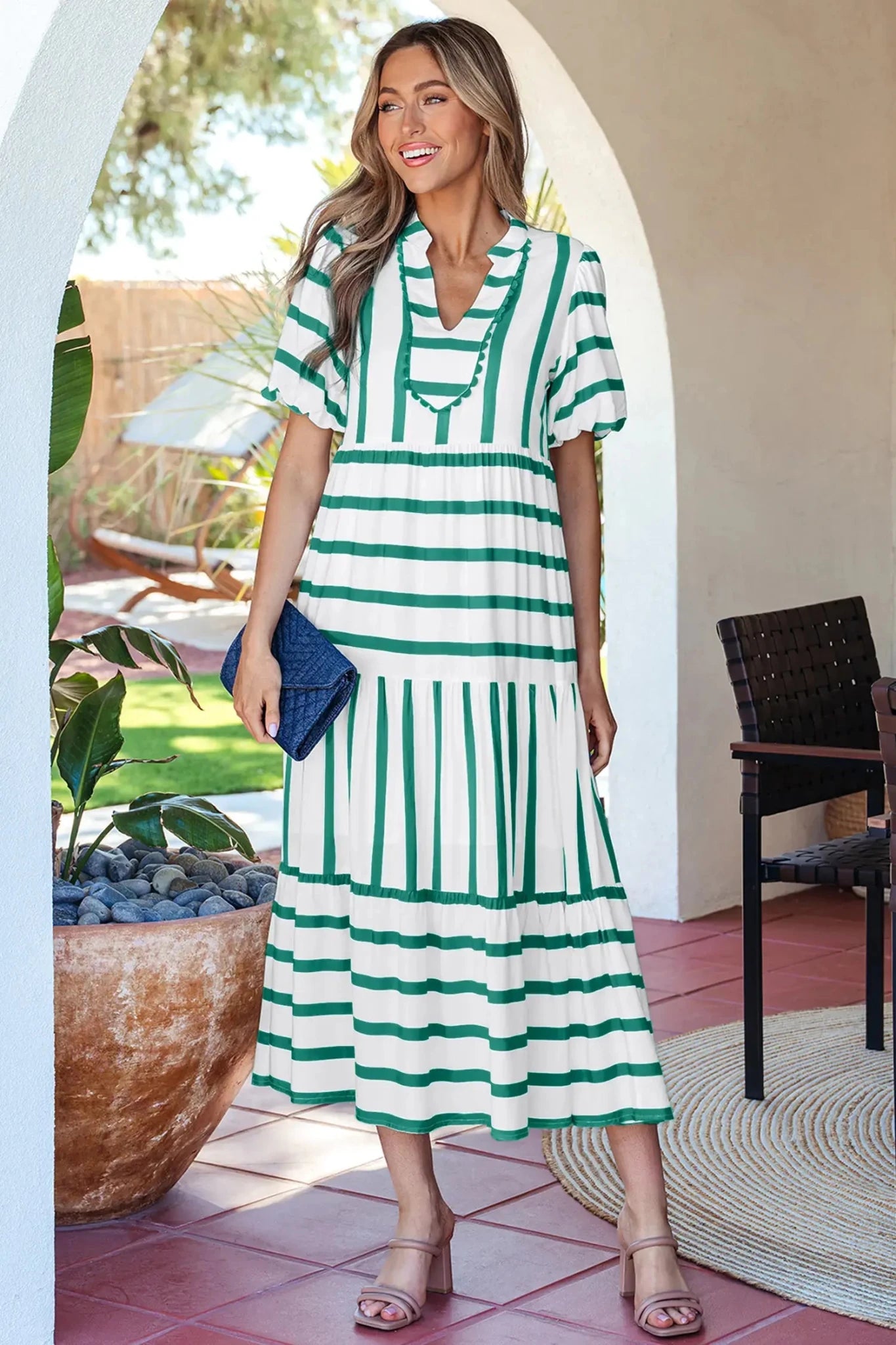 Woman in a green and white striped dress standing in a garden setting.