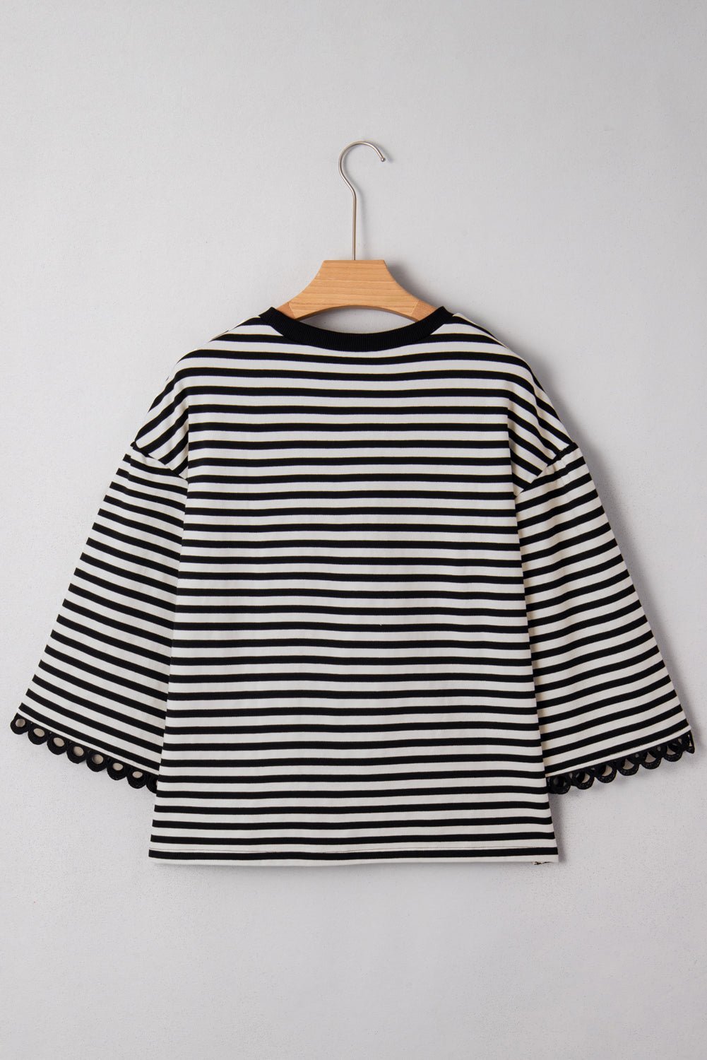 Black and white striped shirt on a hanger against a gray background