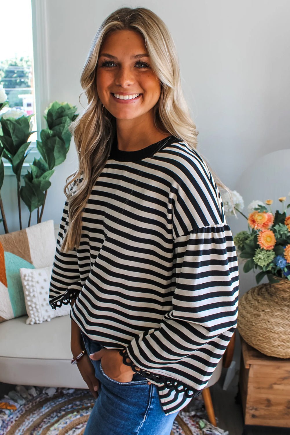 Woman wearing a black and white striped sweater in a cozy living room.