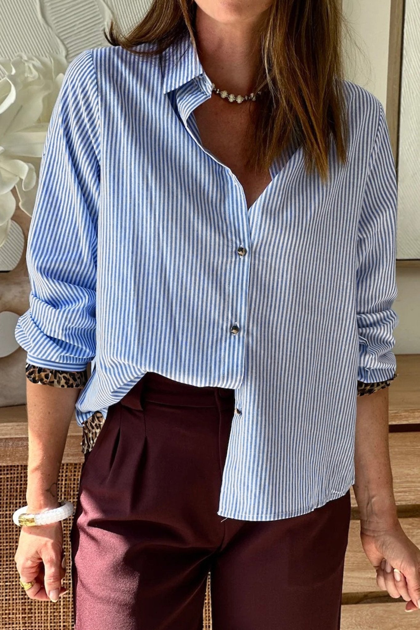 Person wearing a blue and white striped shirt with burgundy pants indoors.