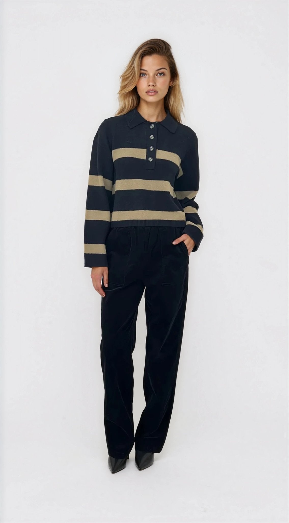 Woman wearing a navy and beige striped sweater with black pants on a white background