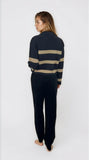 Person wearing a navy sweater with beige stripes and matching pants on a white background