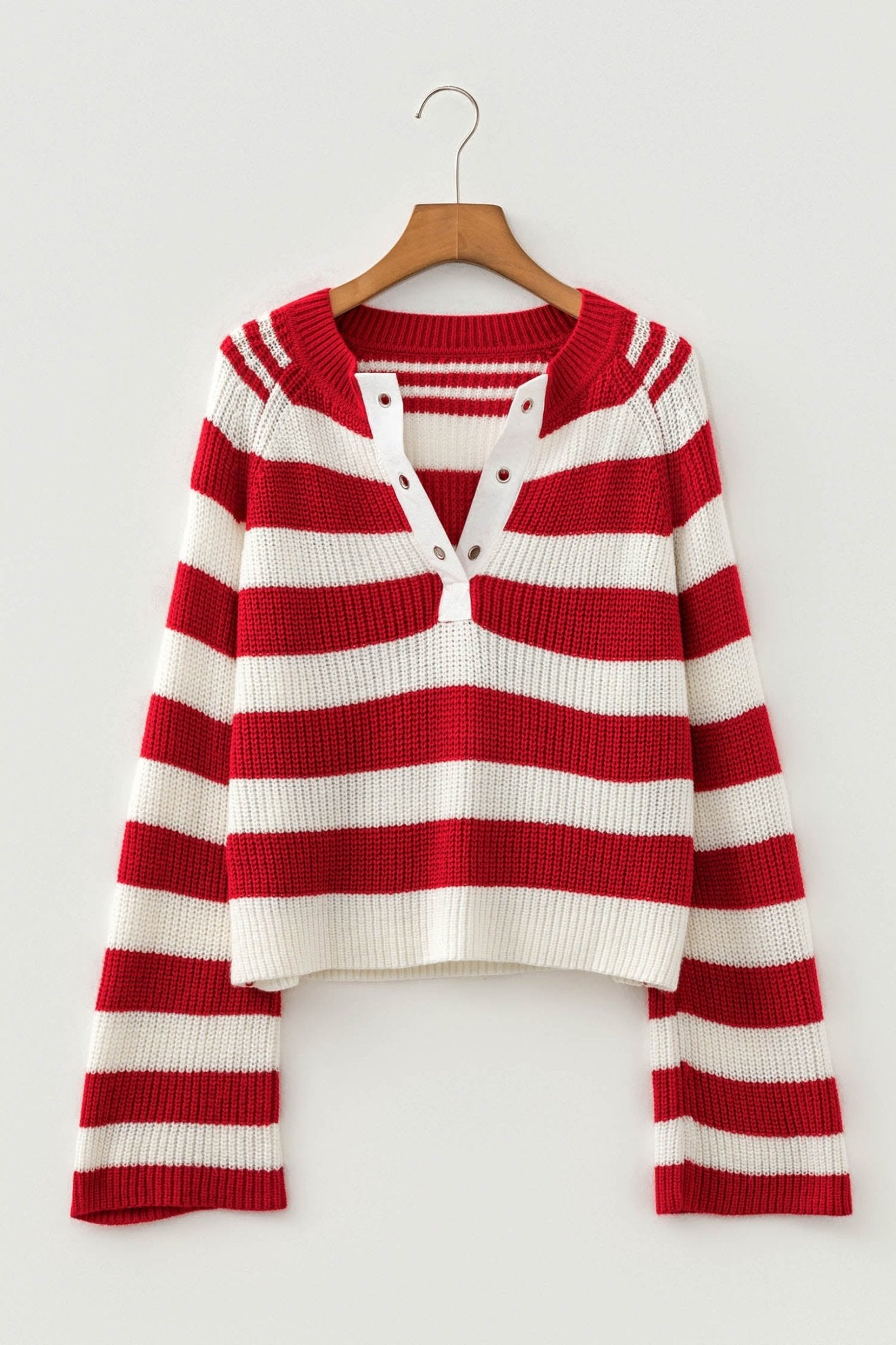 Red and white striped knit sweater with buttoned henley neckline hanging on a wooden hanger.