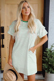 Woman wearing a green and white striped dress standing in front of a wooden door.