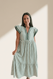 Woman wearing a green and white striped dress against a beige wall.
