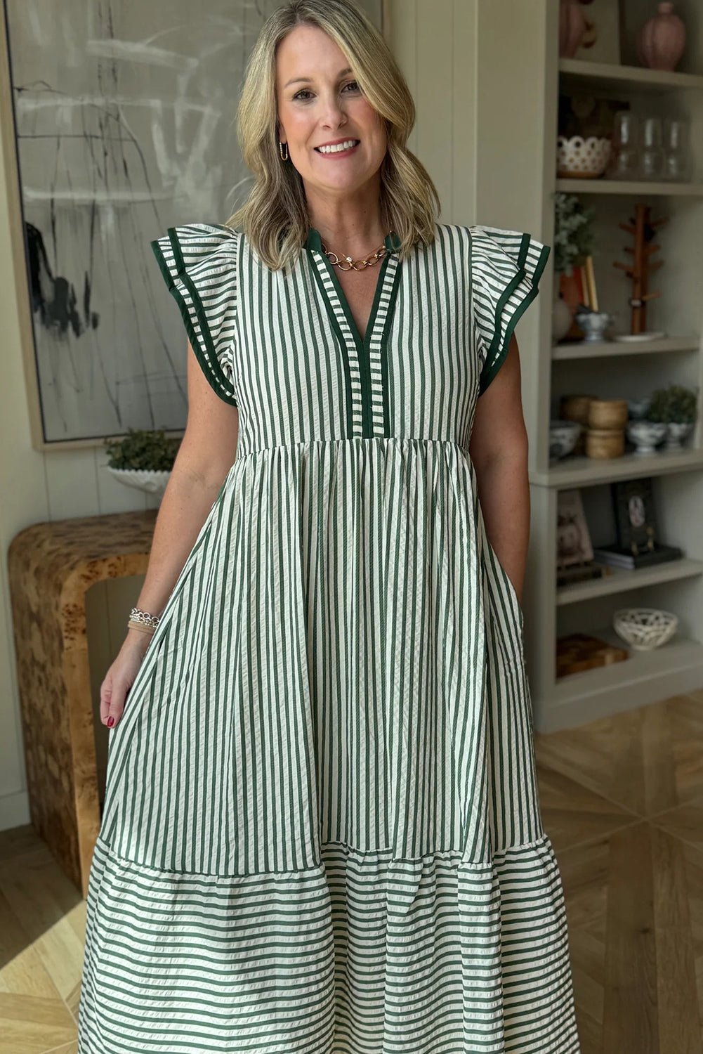 Woman wearing a green and white striped dress in an indoor setting.