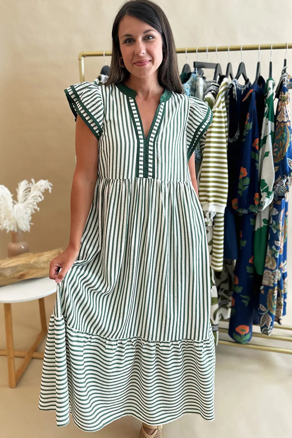 Woman wearing a green and white striped dress in a clothing store.