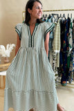 Woman wearing a black and white striped dress in a clothing store.