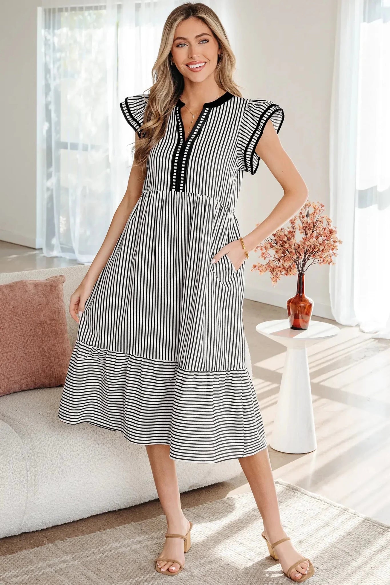 Woman wearing a black and white striped dress in a bright room.